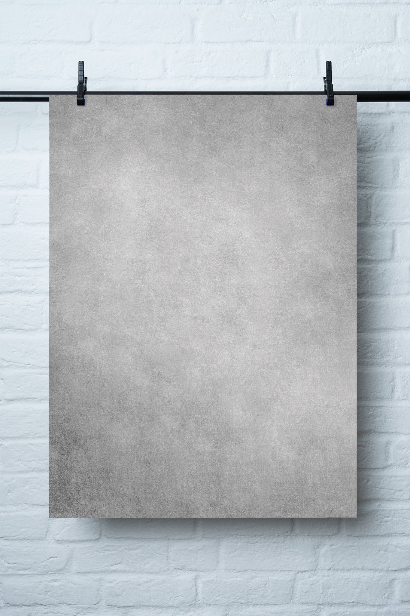 Ein grauer Fotohintergrund mit natürlicher Textur („Salz und Pfeffer“), ideal für Food- und Produktfotografie, aufgehängt vor einer weißen Ziegelwand.