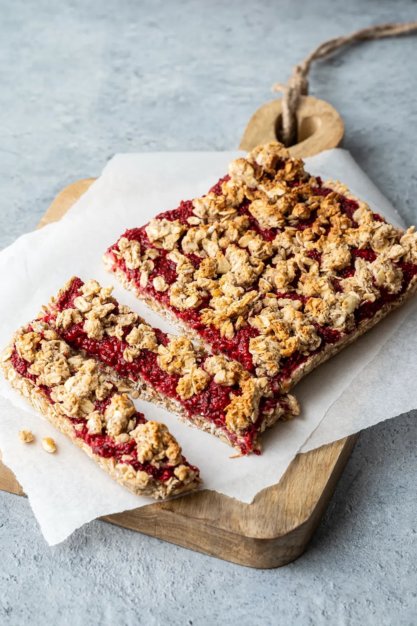 Vinyl Backdrop „Sonnenblumenkerne“ in strukturiertem Grau, verwendet als dezenter Fotountergrund für ein rustikales Foodstyling mit Himbeer-Crumble-Riegel – ideal für natürliche und authentische Produktbilder.