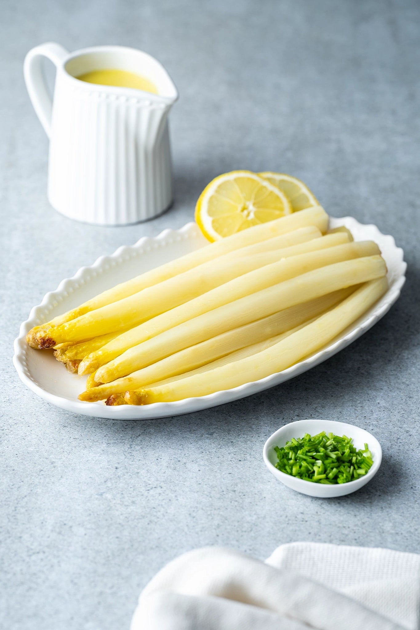 Vinyl Backdrop „Vanilleeis“ in strukturiertem Beige, als eleganter Hintergrund für ein Foodstyling mit weißem Spargel, Zitronenscheiben und Sauce Hollandaise – perfekt für frische, saisonale Produktfotos.