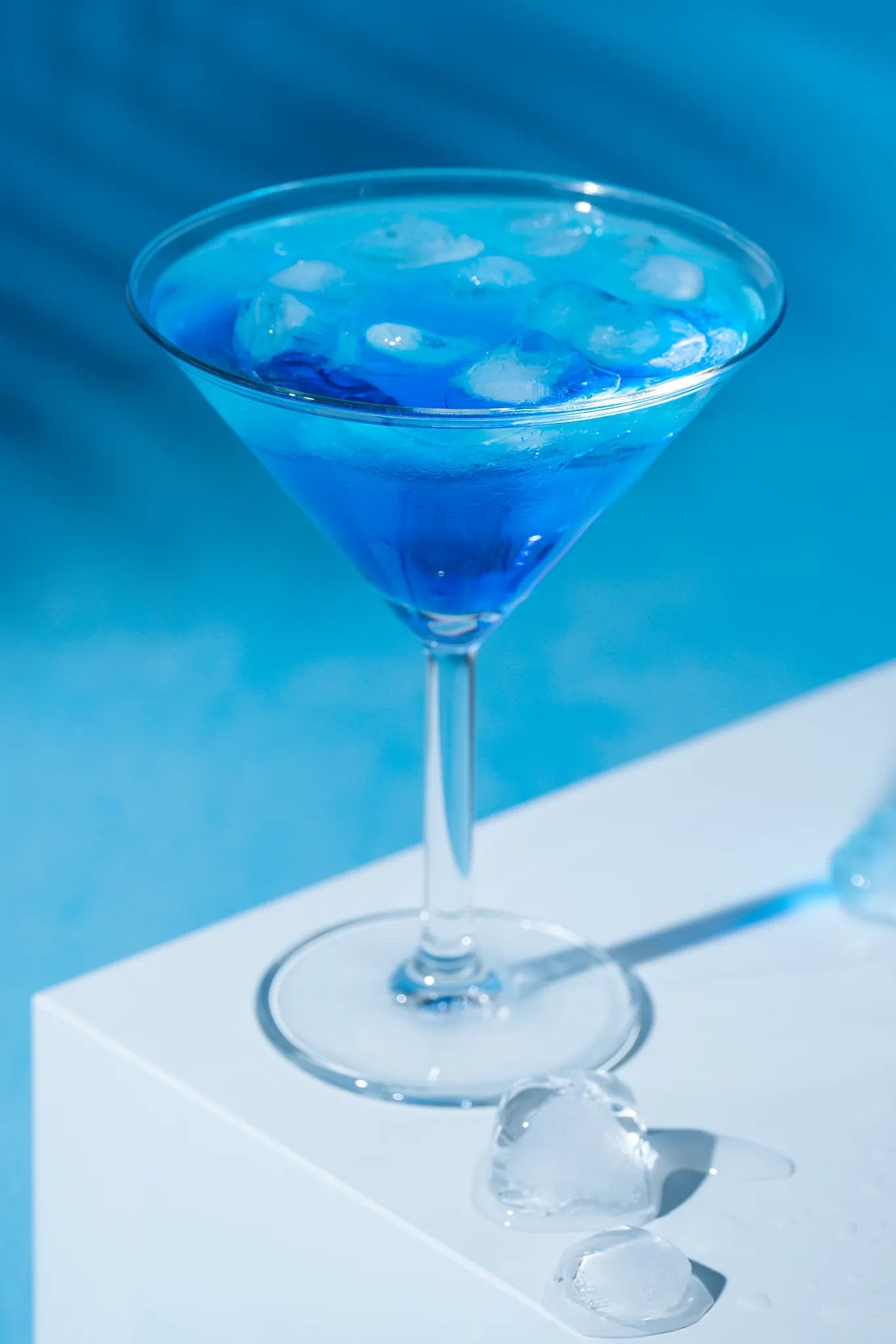 Getränkefotografie Martini-Glas mit blauem Cocktail auf Backdrop „Eisblau Textur“ – heller blauer Fotohintergrund