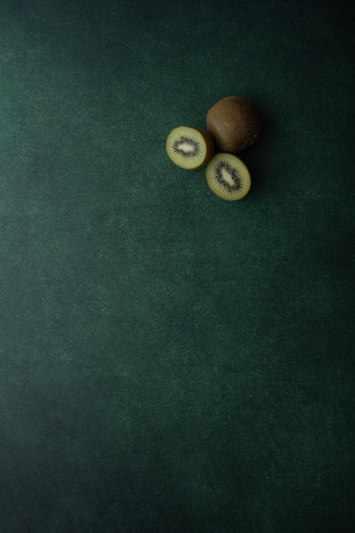 Foodfotografie aufgeschnittene Kiwi auf Backdrop „Feldsalat“ – dunkelgrüner Fotohintergrund von BACKDROP SHOP