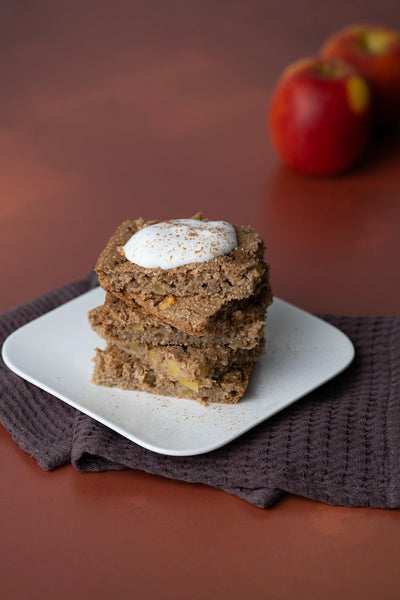 Gestapelte Apfel-Haferkuchen mit Schlagsahne und Zimt auf Backdrop „Kürbissalat" – erdiger orange-brauner Fotohintergrund, Herbststimmung